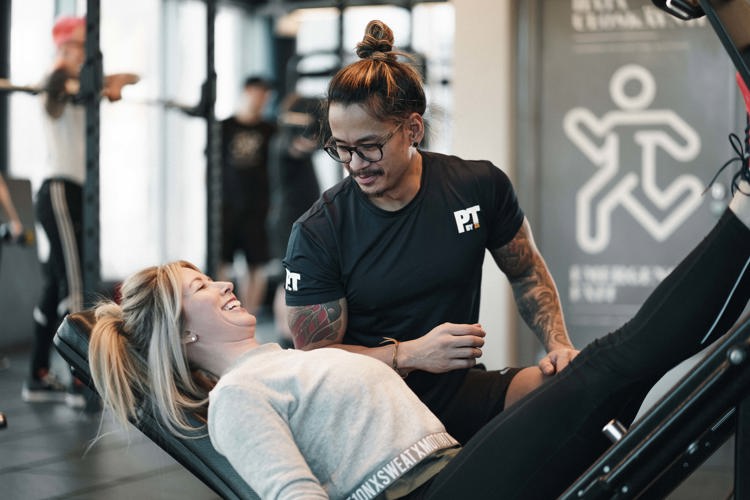 Personal trainer instructing a female client doing a leg press exercise